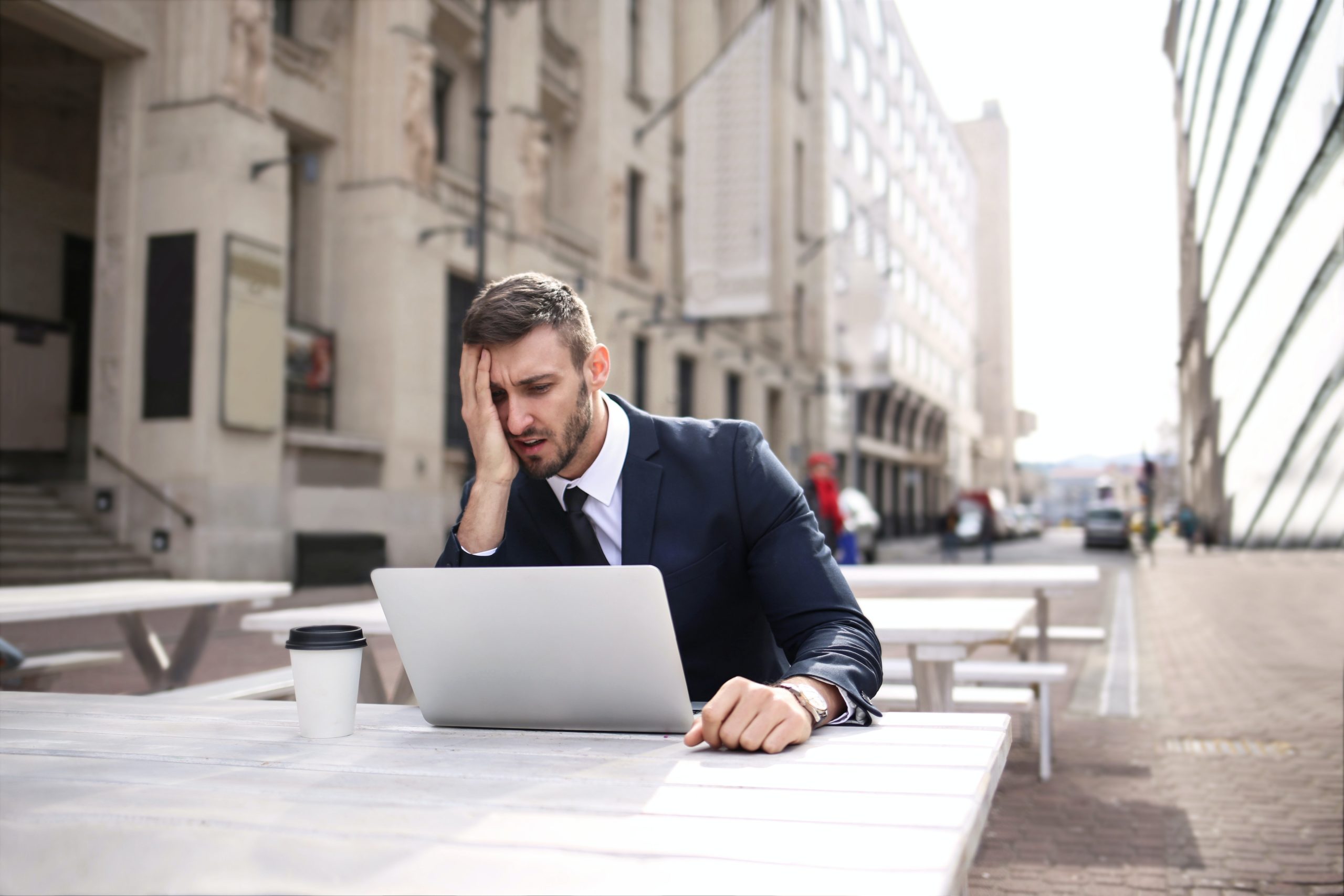 Stressed-looking man in a business suit in front of a laptop.