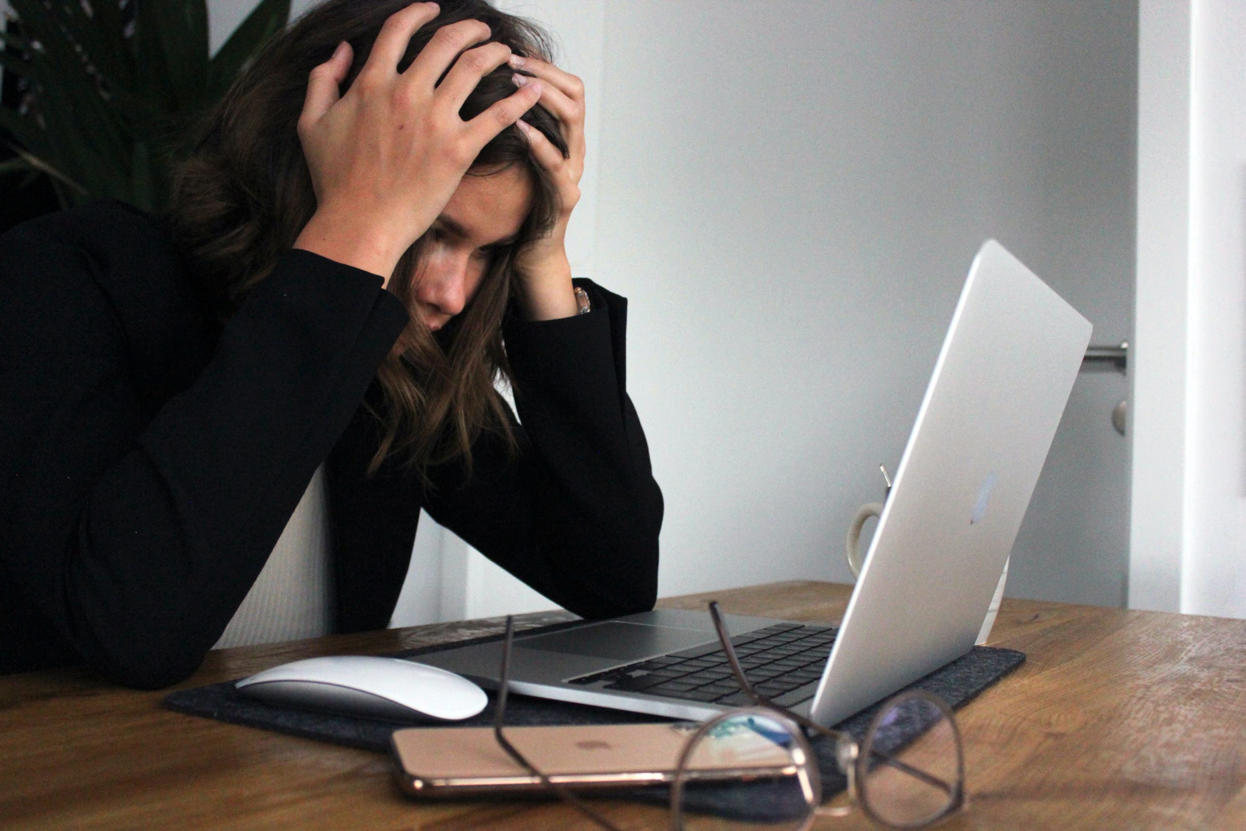 A businesswoman who looks stressed and frustrated. in front of a laptop