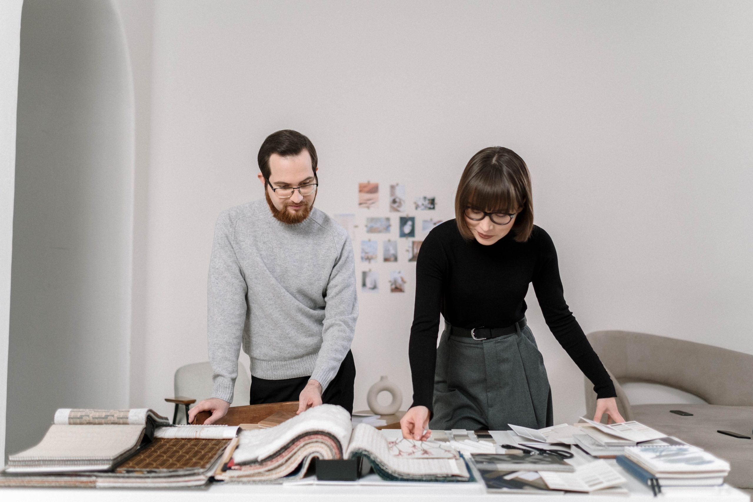 A man and a woman look at fabric swatches at a desk.