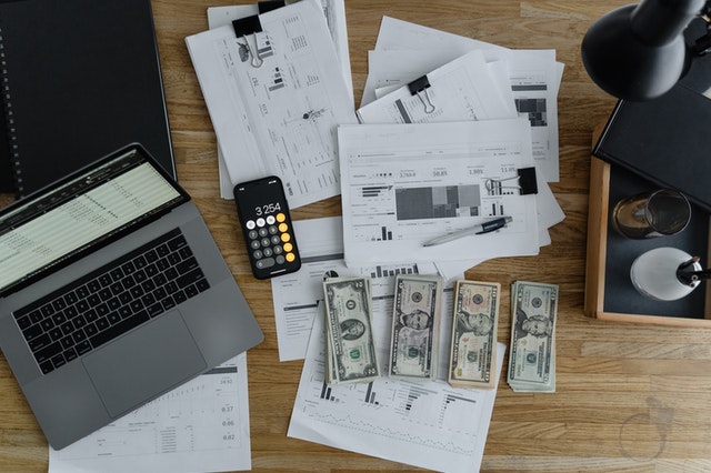 Office table with laptop, cash and documents.