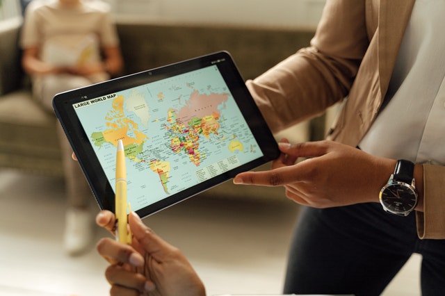 Close-up of a person holding a tablet displaying a world map.