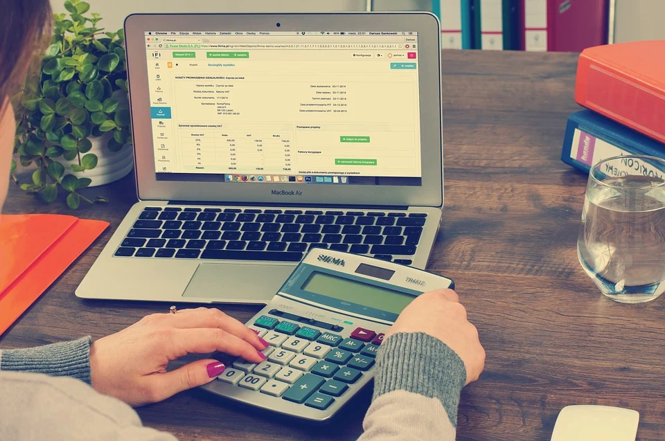 A woman working on bookkeeping software and calculator