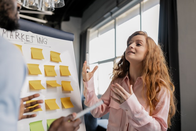 A woman talking about marketing near a board with post-its.