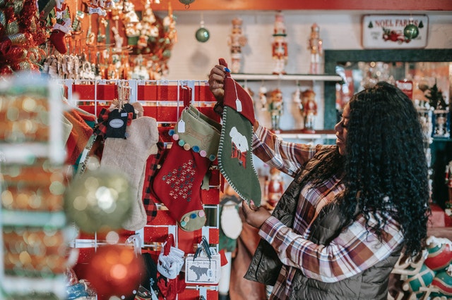 A smiling woman chooses Christmas decorations in a store.