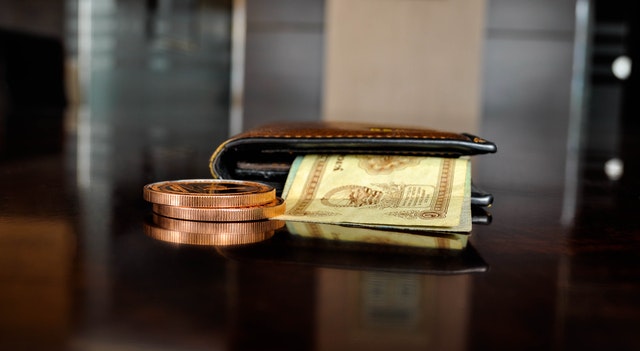 Brown leather bifold wallet with money sticking out.