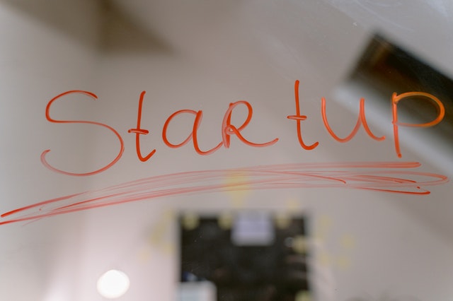 The word “startup” written in red ink on transparent glass